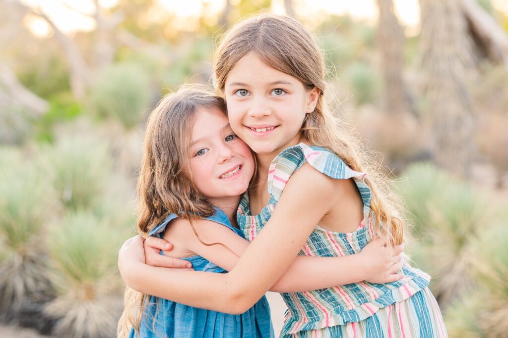 Two sisters smiling in front of Joshua trees for family photoshoot in Lancaster, California