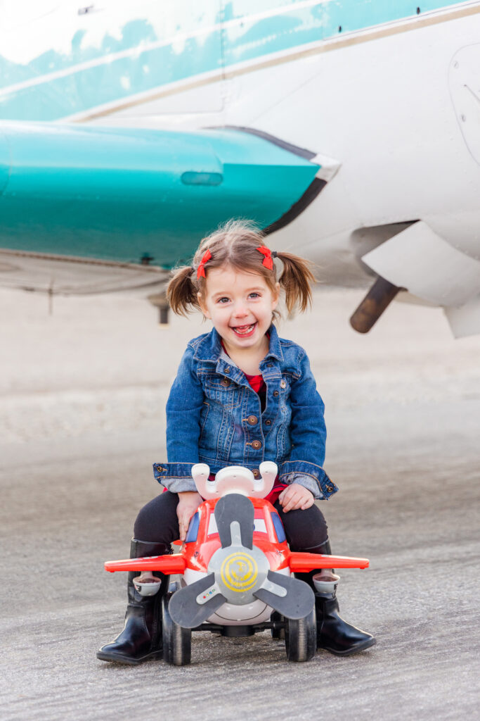 Girl smiling with airplane during aviation family photoshoot in Tehachapi, California