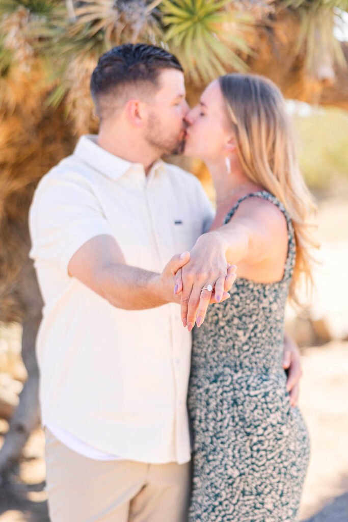 Engaged couple kisses and shows off engagement ring at Joshua Tree, California