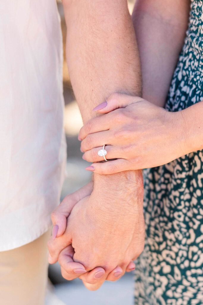 Close-up image of couple holding hands with new engagement ring