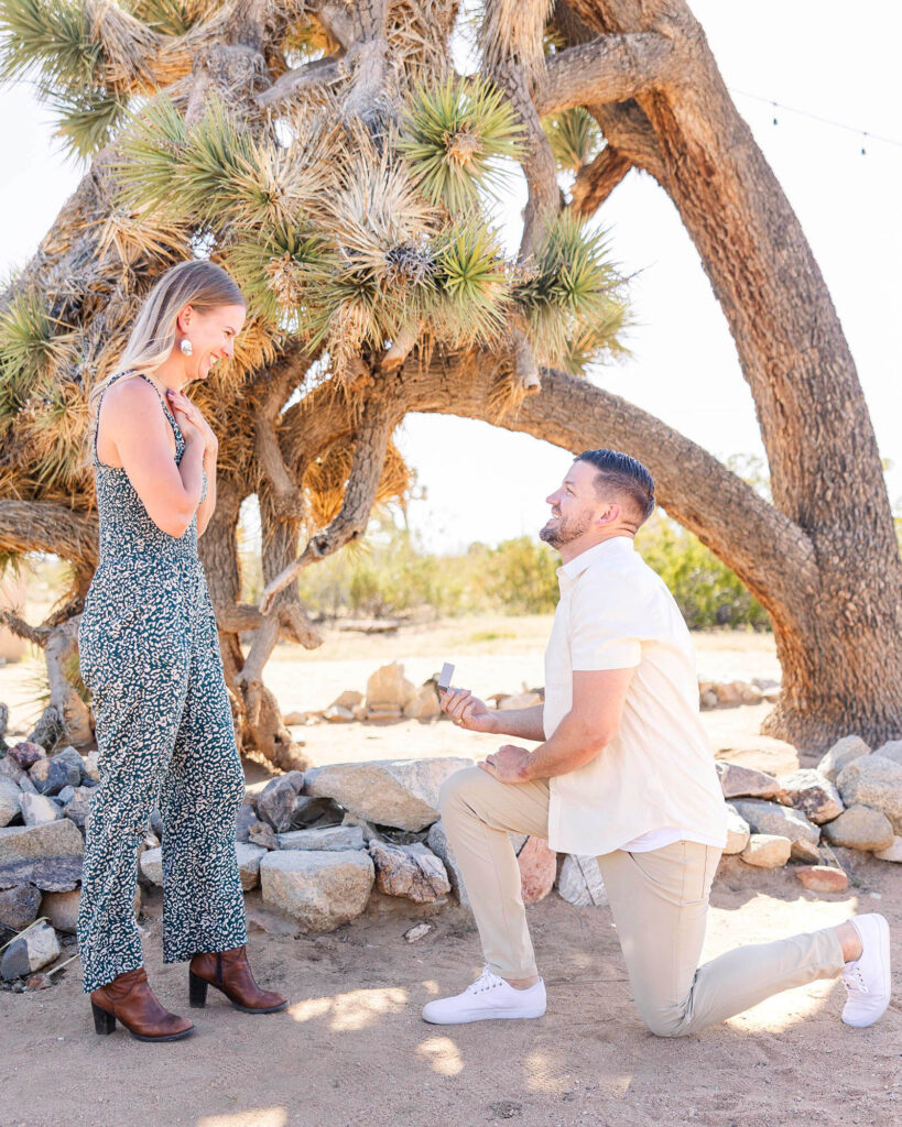 Man on one knee, proposing to surprised girlfriend at Joshua Tree, California