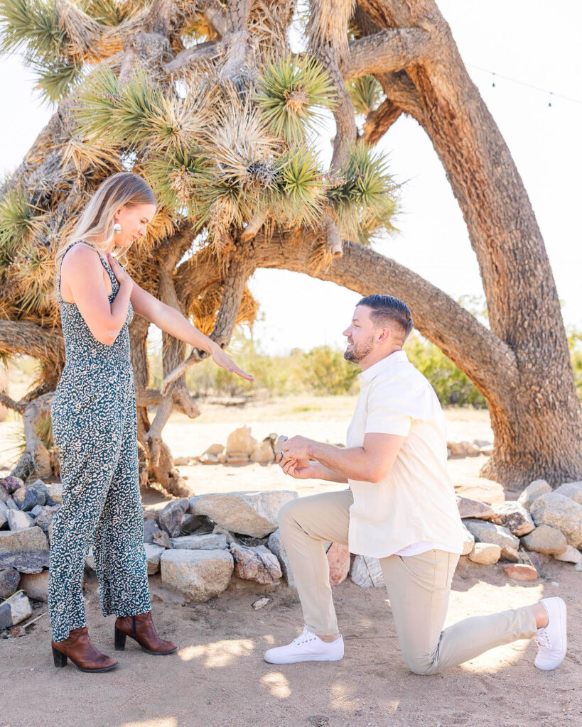 Man on one knee, proposing to surprised girlfriend at Joshua Tree, California