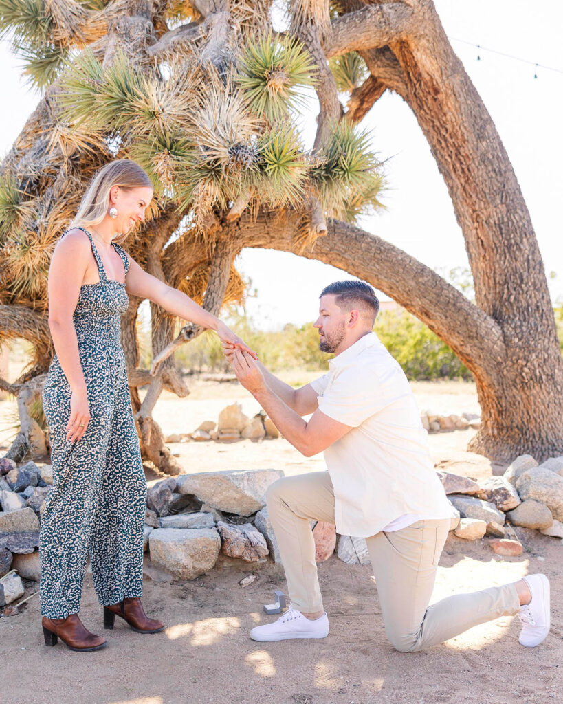 Man on one knee, proposing to surprised girlfriend at Joshua Tree, California