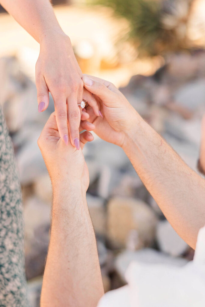 Close-up of man putting engagement ring on fiancée's finger