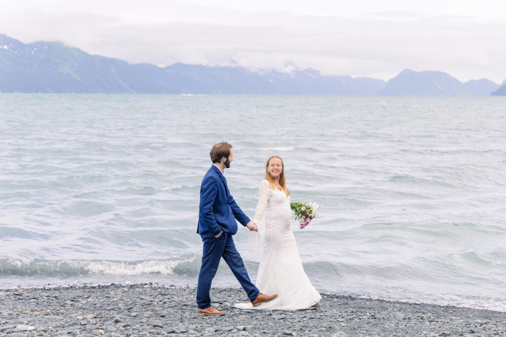 Wedding couple walks along beach in Seward, Alaska during elopement