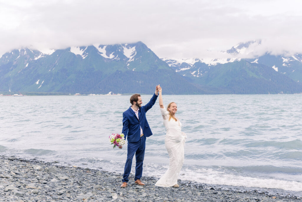 Wedding couple dances on beach in Seward, Alaska during elopement