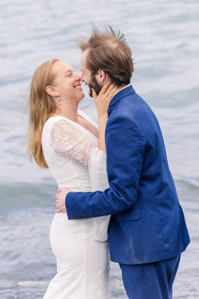 Wedding couple smiles on beach in front of mountains in Seward, Alaska during adventure elopement