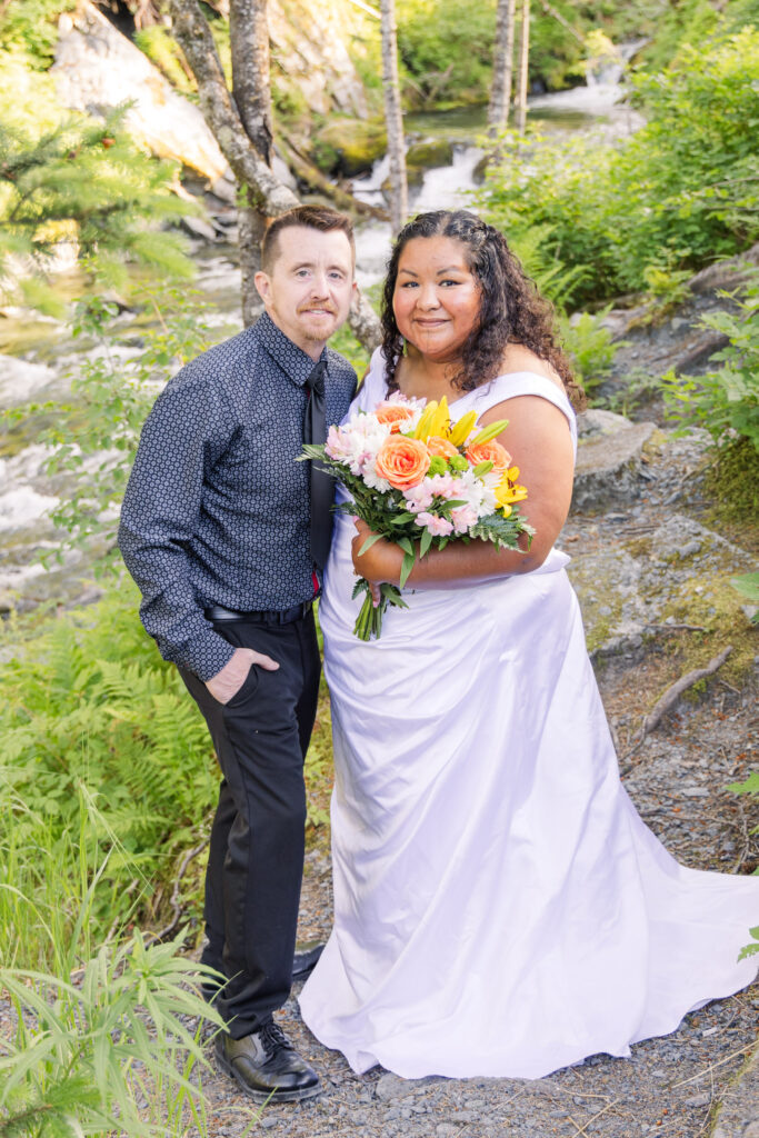 Couple eloping in fairytale tree forest river waterfall setting in Whittier, Alaska