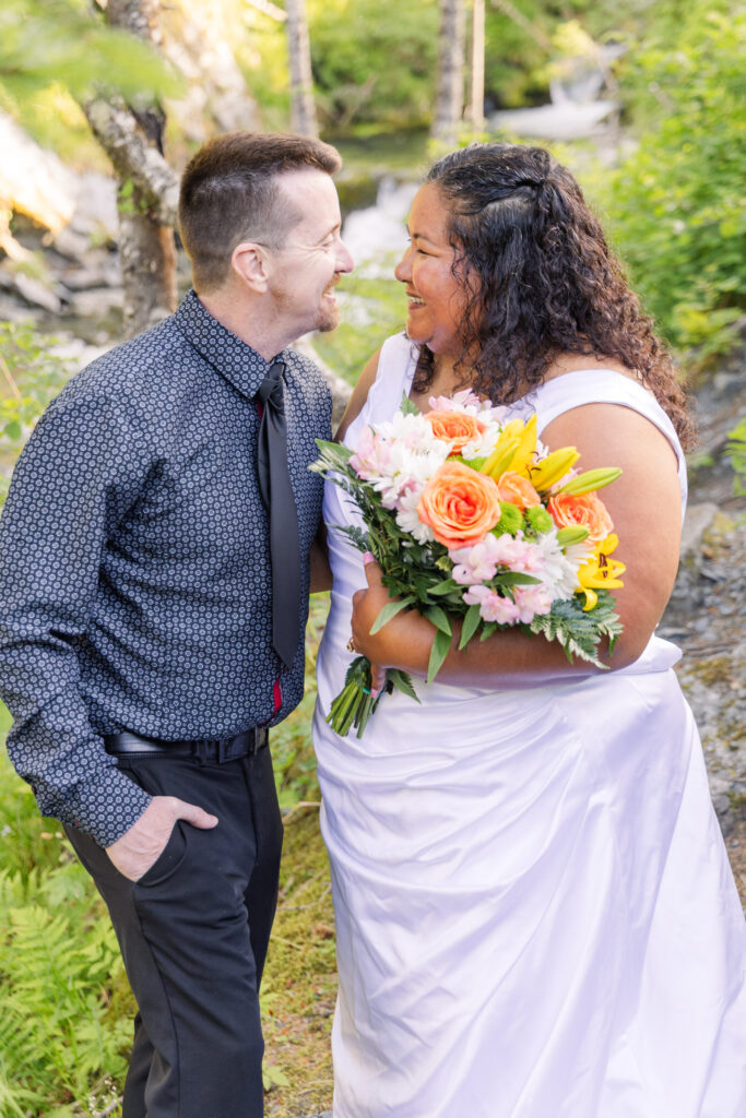 Couple eloping in fairytale tree forest river waterfall setting in Whittier, Alaska