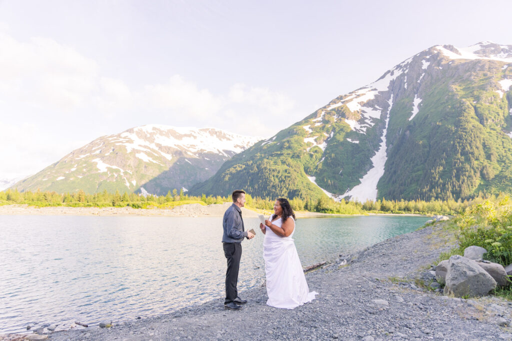 Couple exchanging wedding vows at scenic elopement in front of glacier, mountain, and lake in Whittier, Alaska