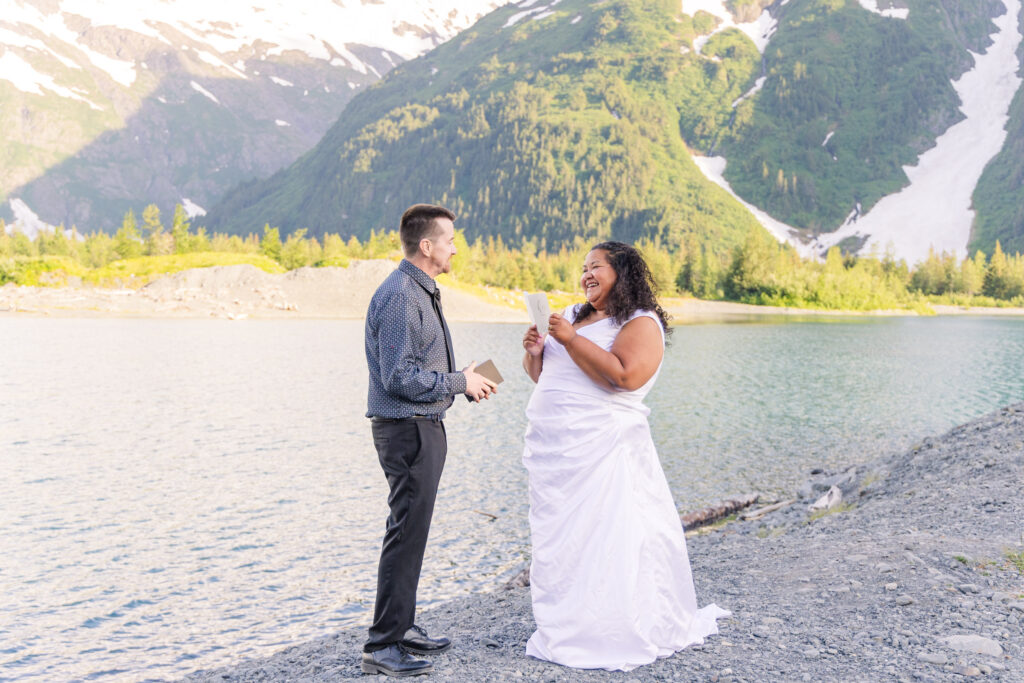 Couple exchanging wedding vows at scenic elopement in front of glacier, mountain, and lake in Whittier, Alaska