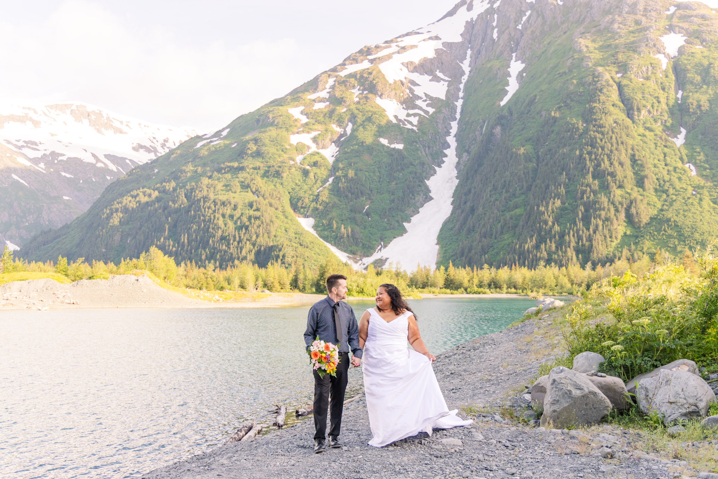 Bride and groom walking together in front of glacier during elopement in Whittier, Alaksa