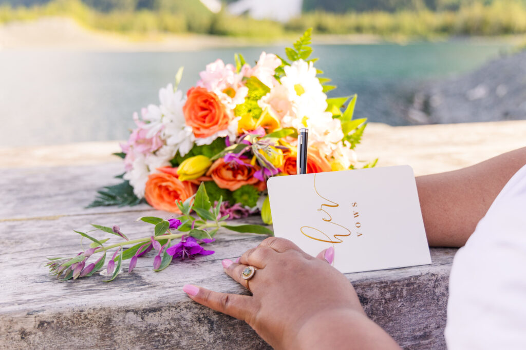 Bride writing wedding vows at scenic elopement in front of glacier, mountain, and lake in Whittier, Alaska