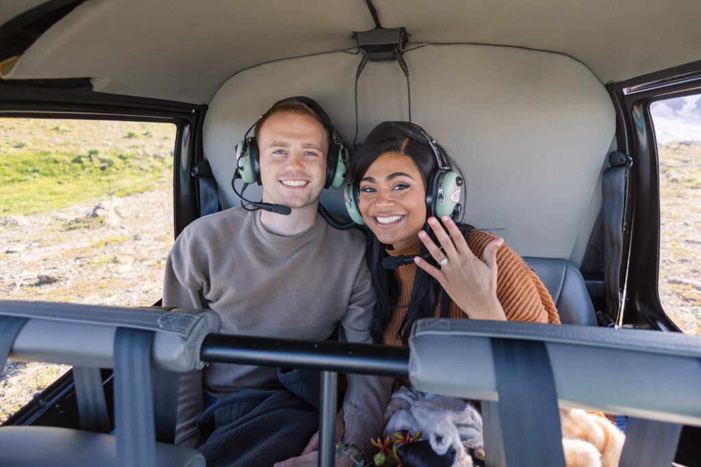 Girl shows off engagement ring excitedly while riding in a helicopter in Alaska.