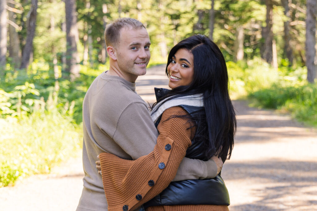 Couple smiles on a tree-lined path in Girdwood, Alaska.