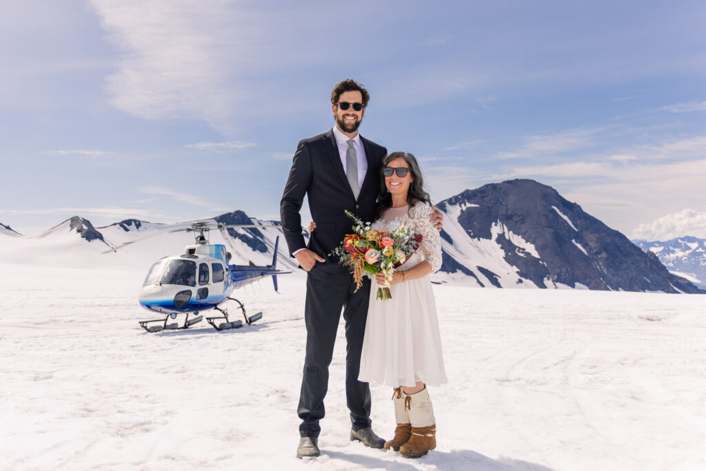 Eloping couple in front of helicopter on snowy glacier during Alaska elopement
