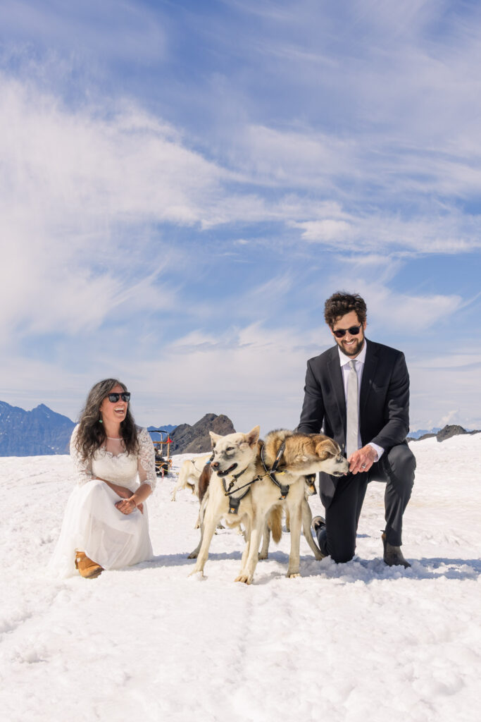 Eloping couple with sled dogs at glacier dogsled camp during Alaska elopement