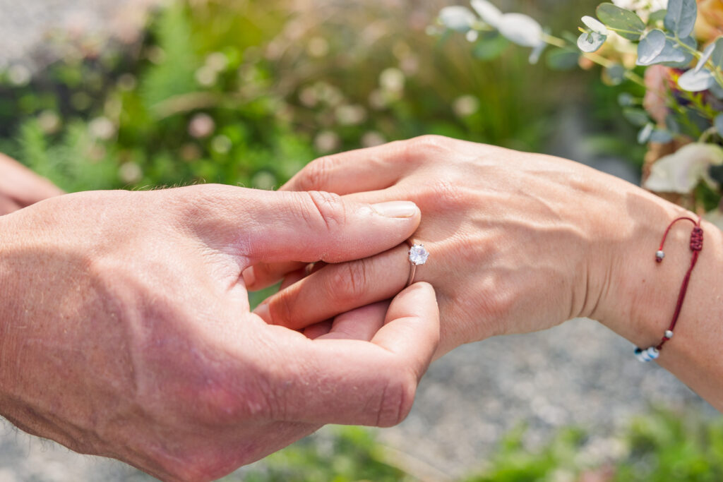 Close-up detail photo of groom putting wedding ring on bride's hand during Alaskan elopement