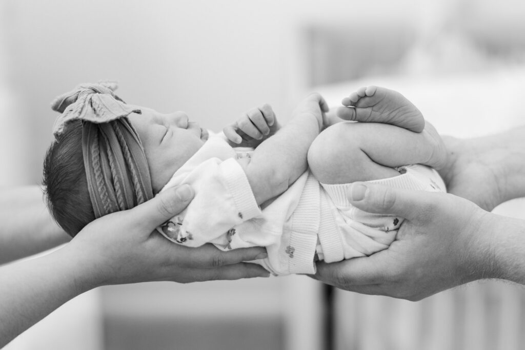 close up detail of mom and dad's hands holding baby in nursery