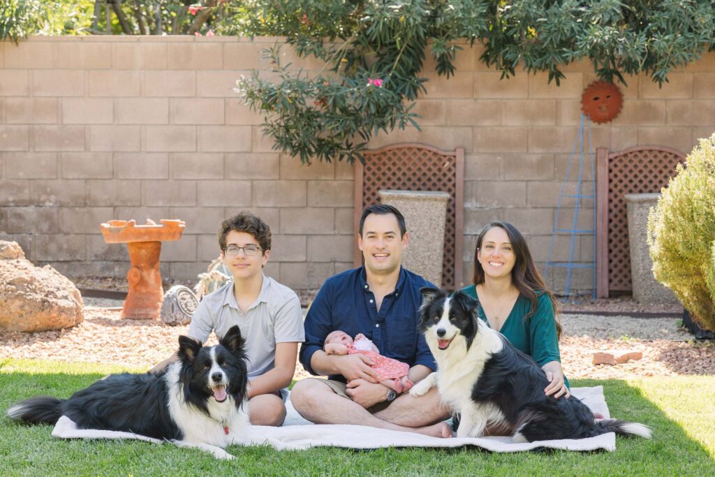 lifestyle newborn family photo with dogs in backyard