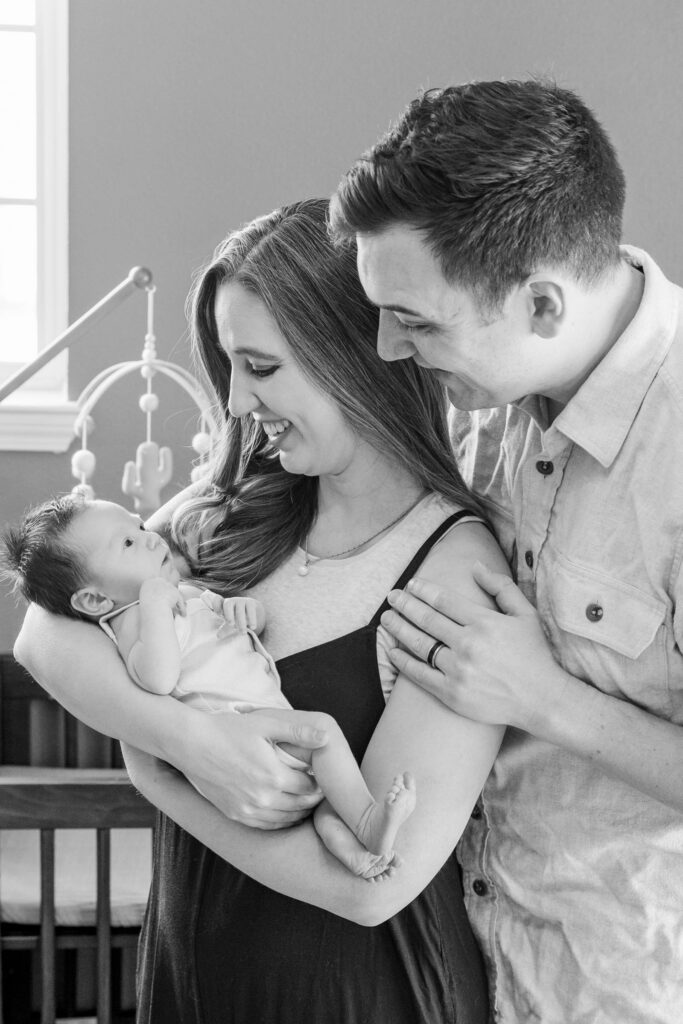 newborn being held by mother and father in nursery