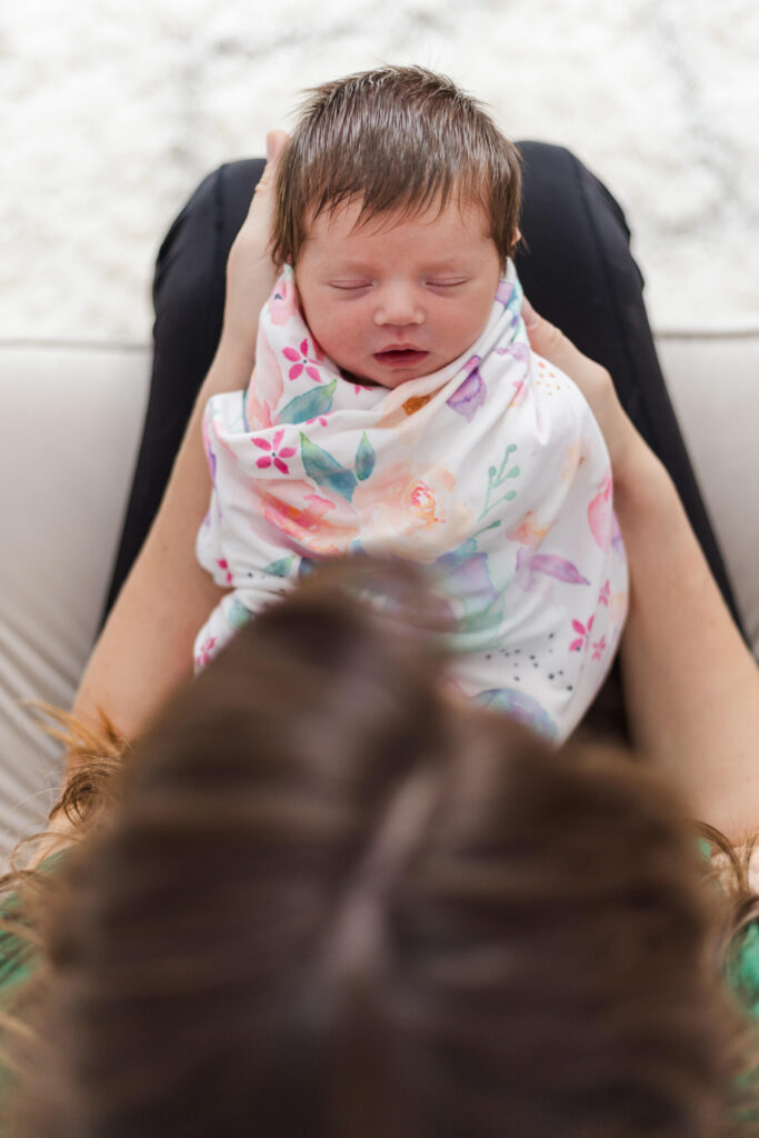 mother looking down lovingly at sleeping baby while sitting on nursing chair