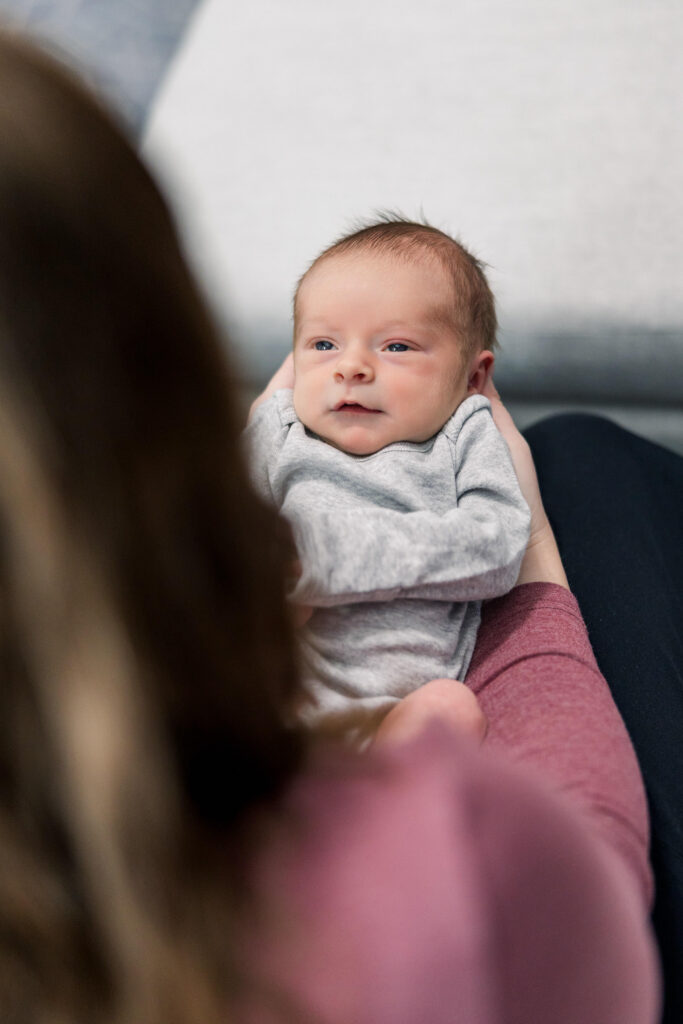 mother looking down lovingly at newborn baby while sitting on nursing chair