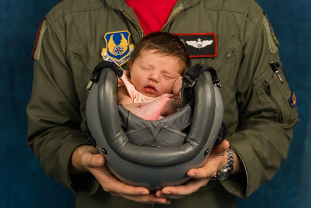 air force pilot holding newborn in flying helmet