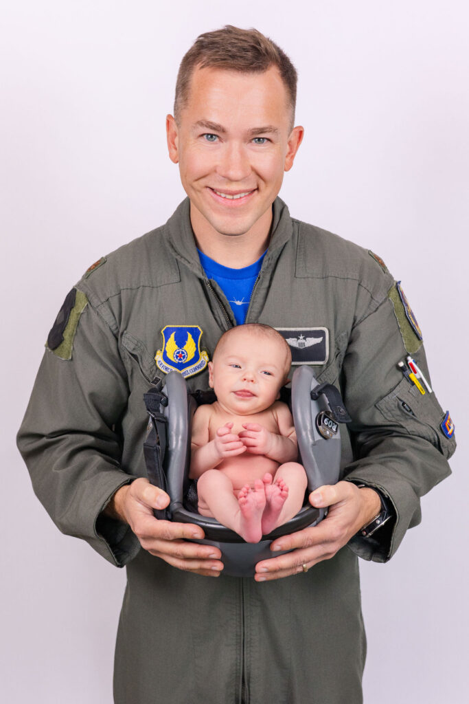 air force pilot in flight suit holding baby in flight helmet during studio newborn session