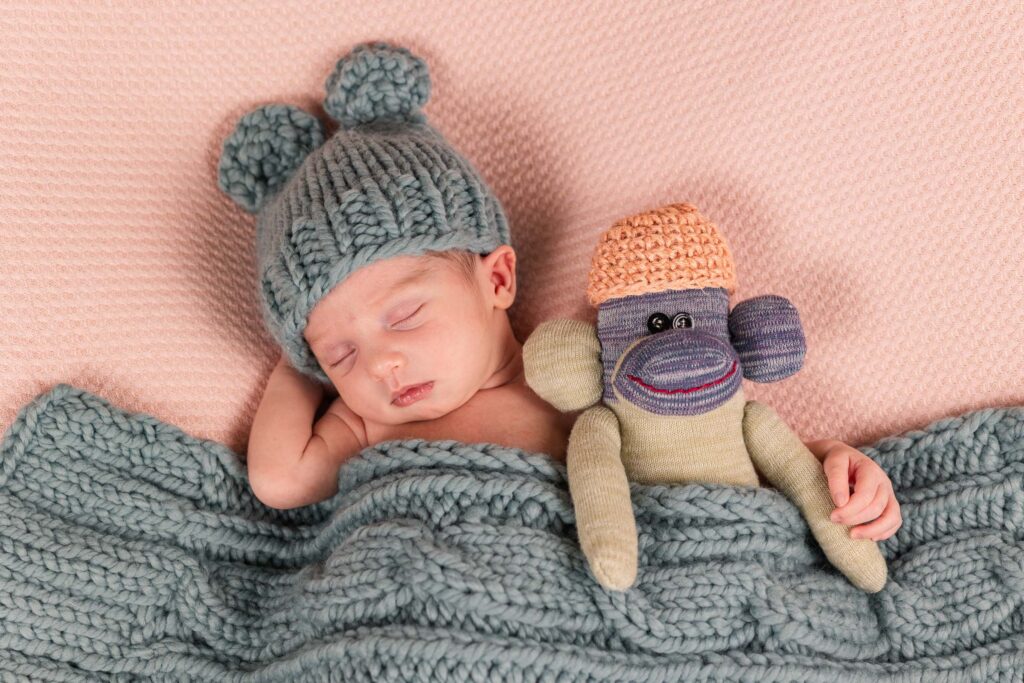 newborn with handmade stuffed monkey and matching knit hat