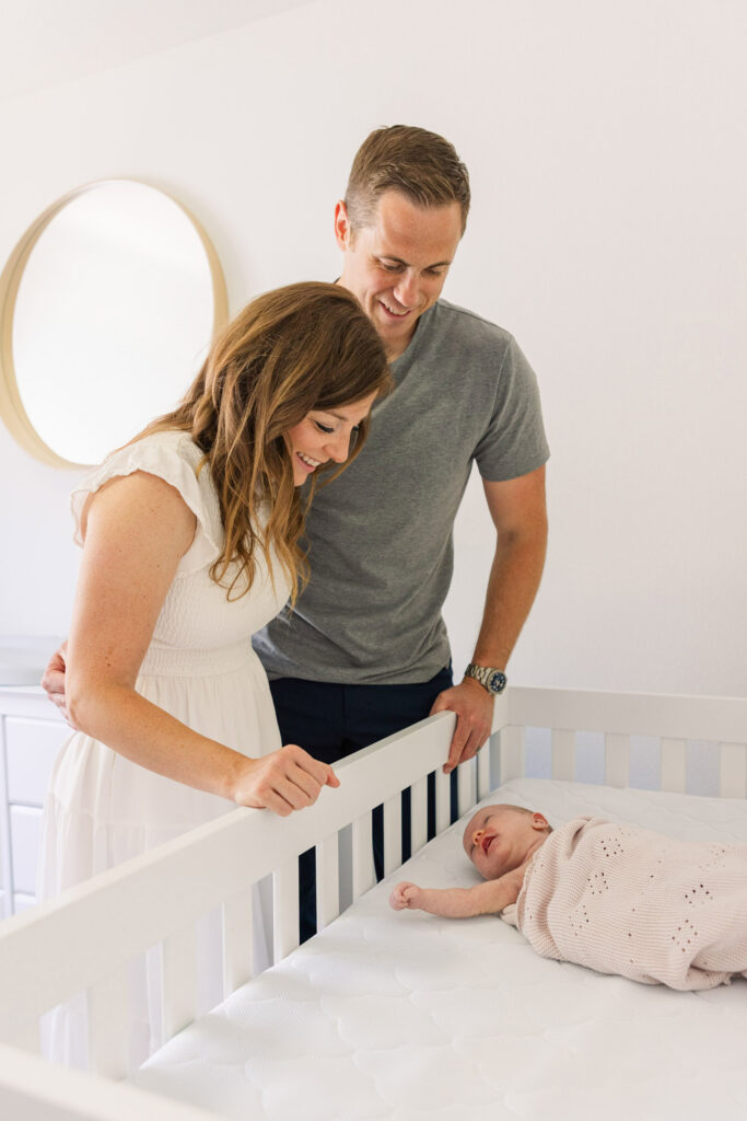 parents smiling at infant in crib during lifestyle newborn session