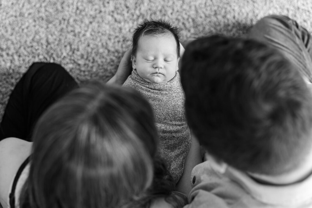 parents looking down at newborn baby they are holding during lifestyle newborn session
