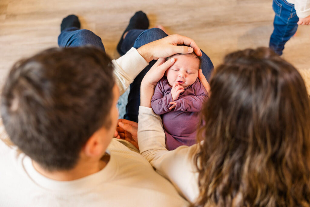 parents looking down at newborn baby they are holding during lifestyle newborn session