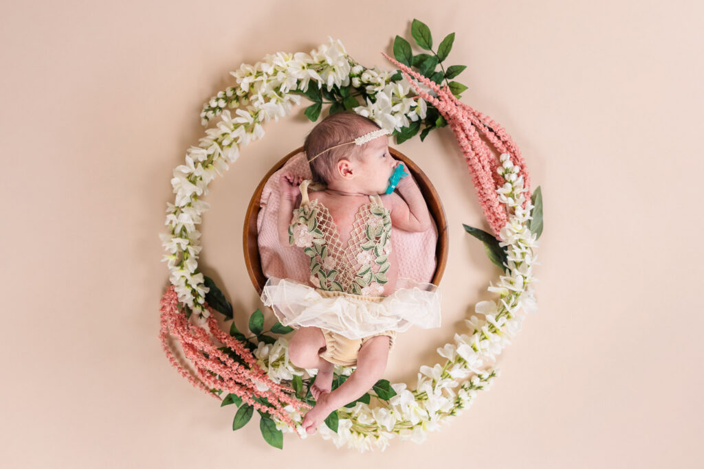 top-down view of newborn girl wearing handmade flower tutu resting inside pink and white flower wreath