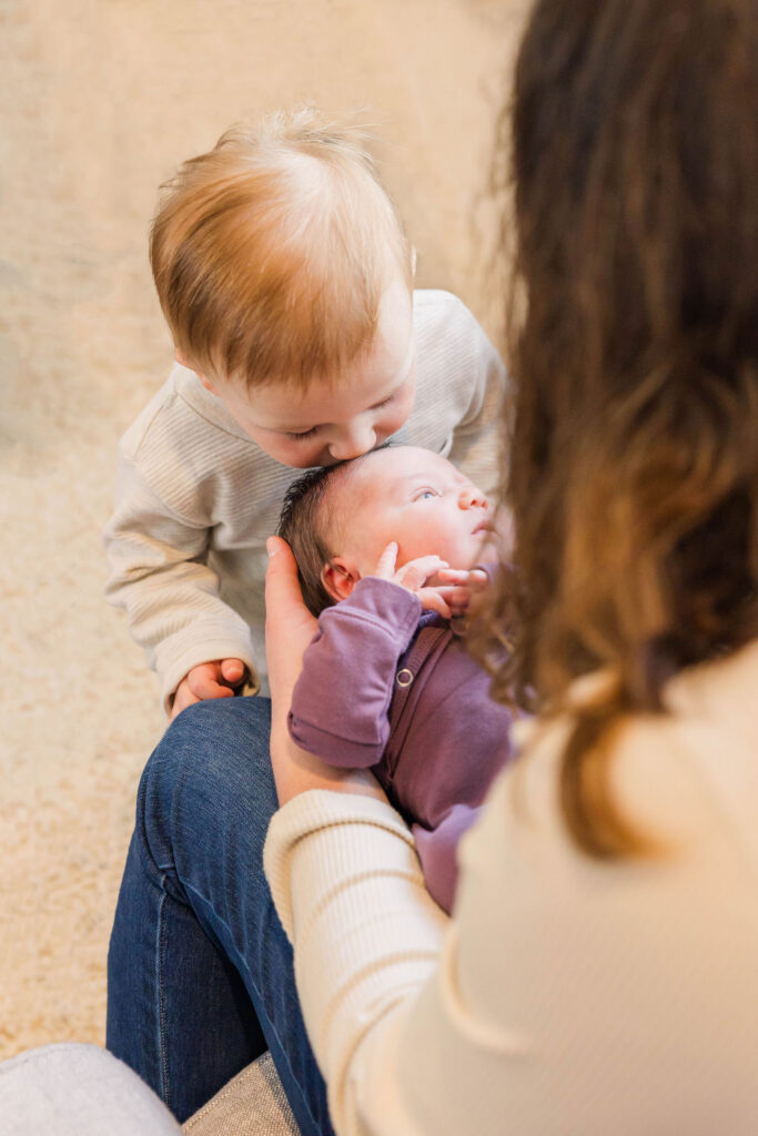 toddler kissing newborn baby in lifestyle session