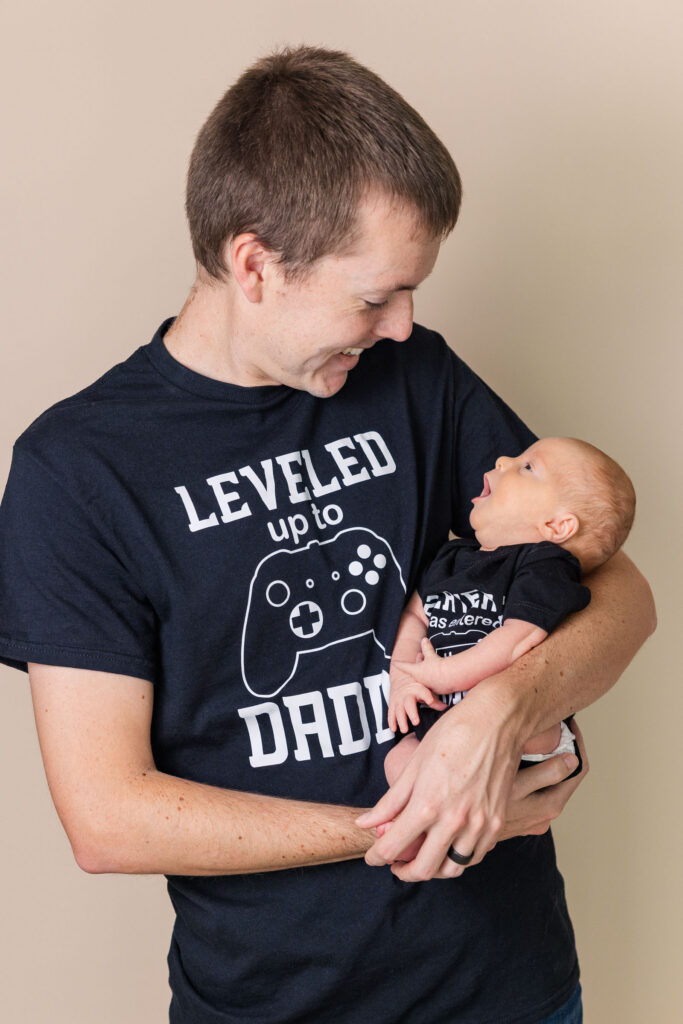 video game themed newborn session with dad looking down at baby