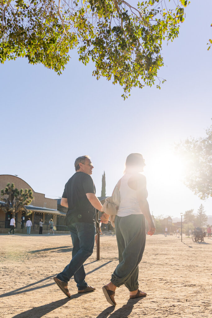 David and Lisa walking hand in hand along Mane Street in the afternoon sunlight.