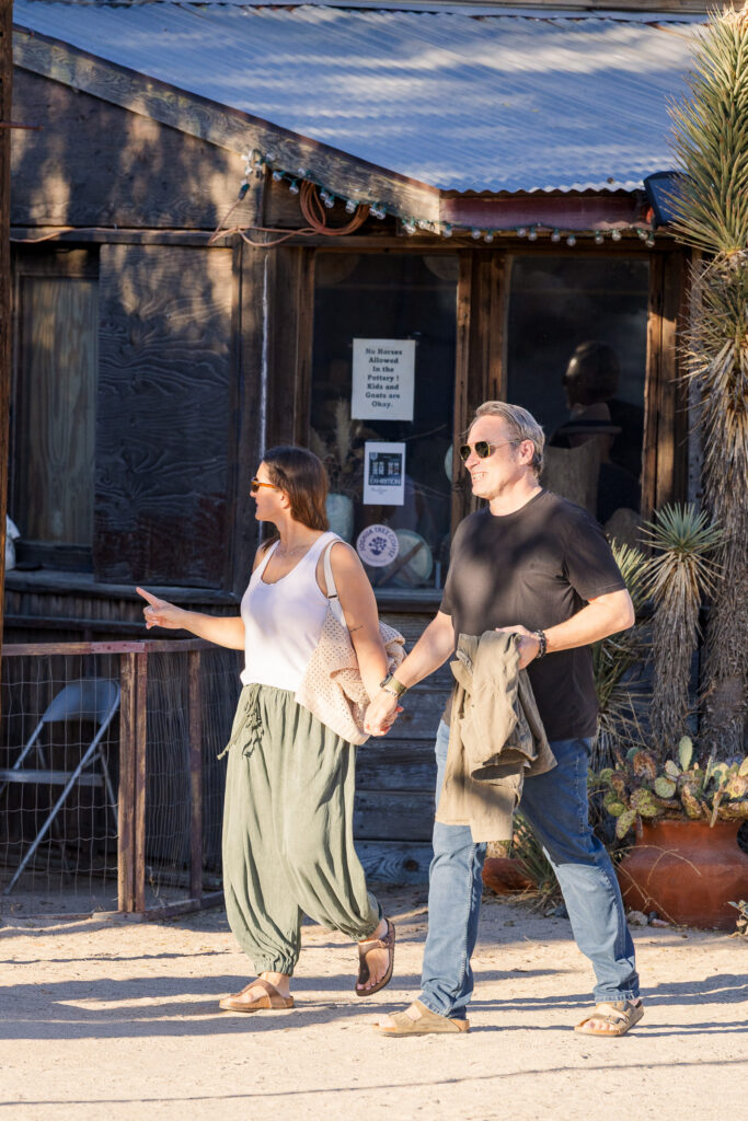 David and Lisa strolling past historic wooden storefronts while exploring Pioneertown together.