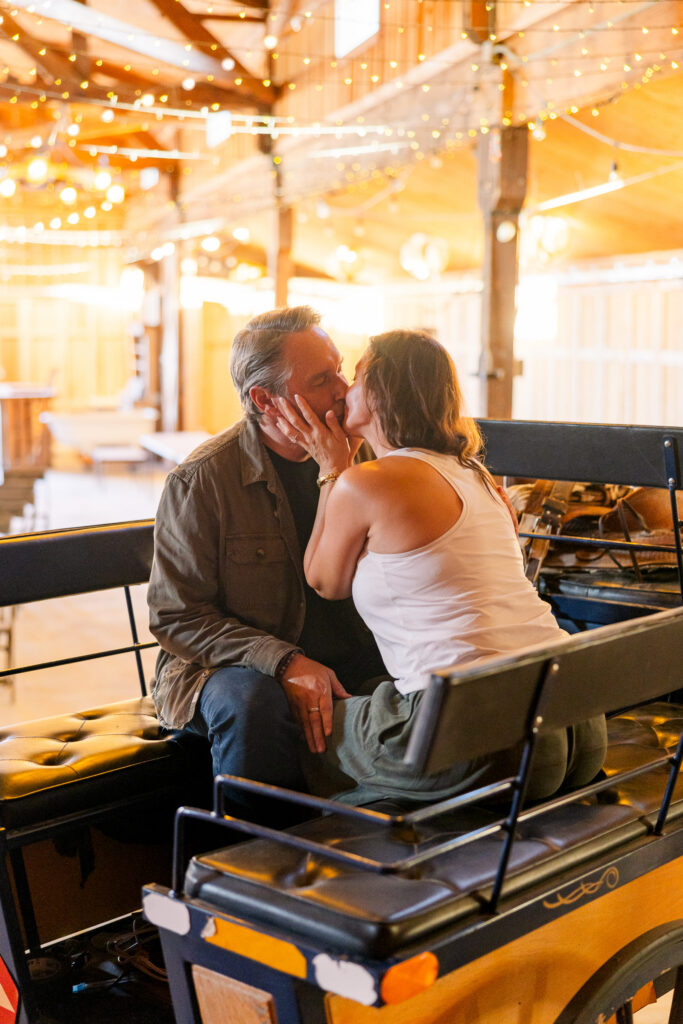 David and Lisa sharing a kiss on an antique wagon beneath the Soundstage's string lights.