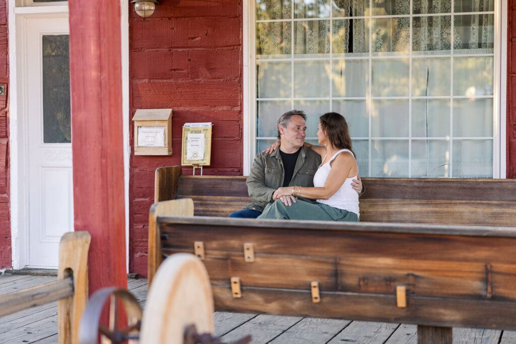 Newly engaged couple snuggled up on The Church in Pioneertown porch.