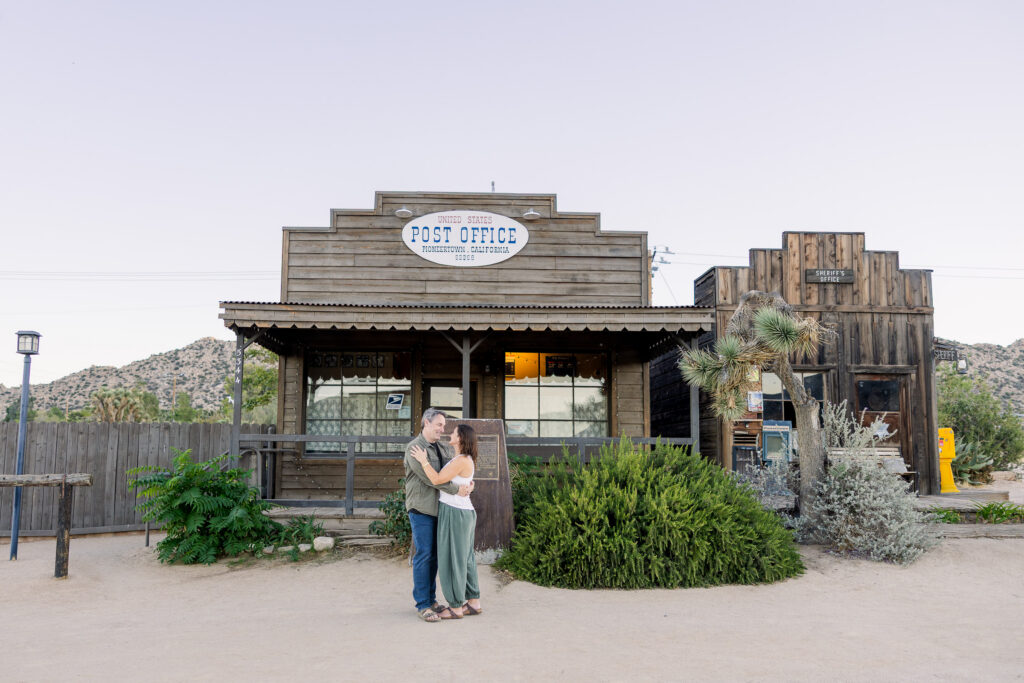 David and Lisa smiling at each other in front of historic Pioneertown Post Office.