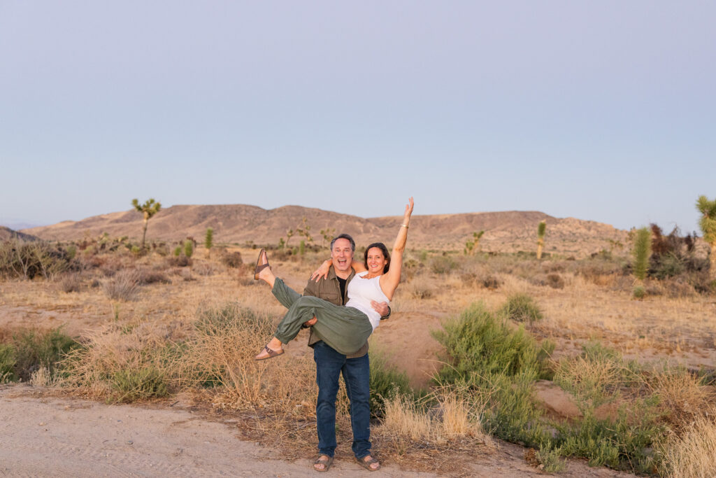 David and Lisa celebrating their engagement in the open desert landscape at sunset.