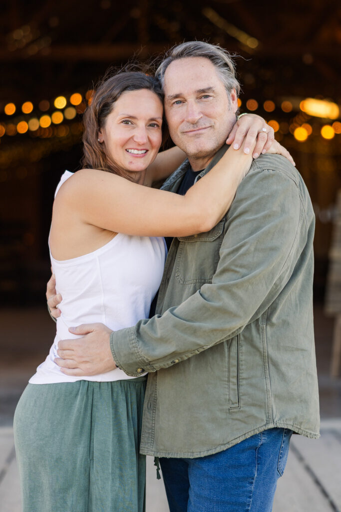 David and Lisa embracing inside the Pioneertown Soundstage, with warm string lights glowing behind them.