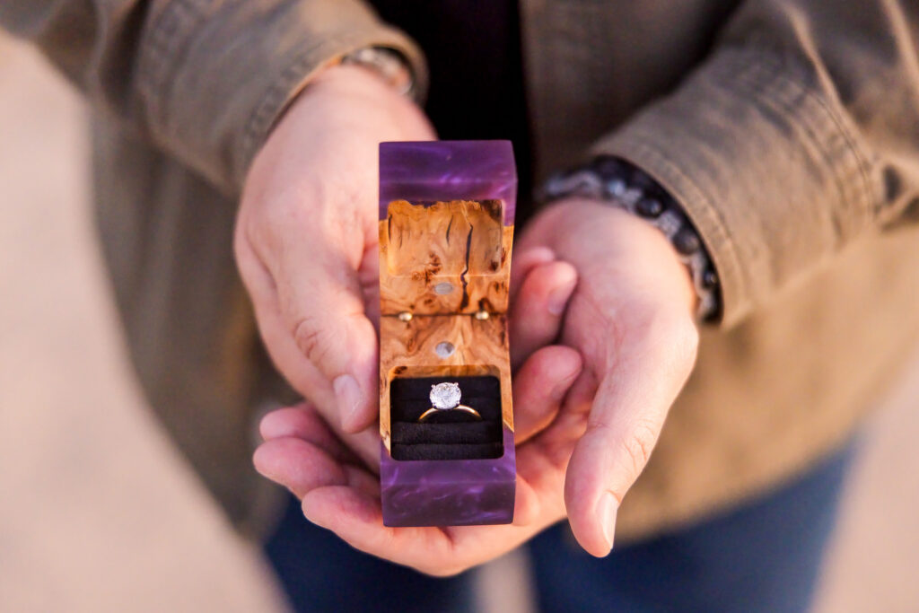 Purple wood-and-resin engagement ring box opened to reveal Lisa's ring.